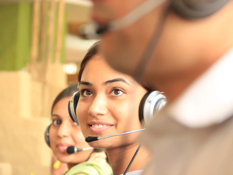Two people wearing telephone headsets working at computers in a bright open office.
