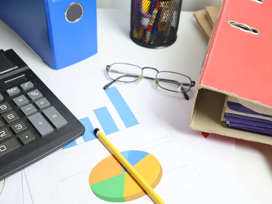 A desk with a calculator, printed charts and ring binders.